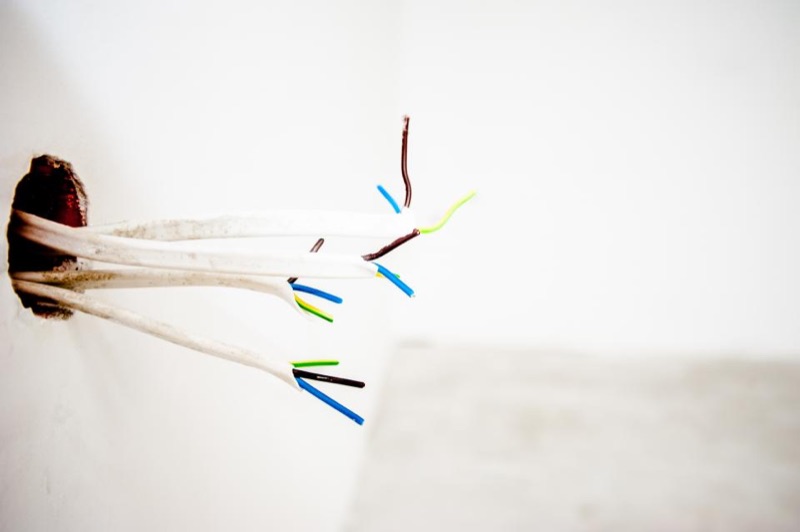 Electrical cables with stripped coloured wires coming out of a wall